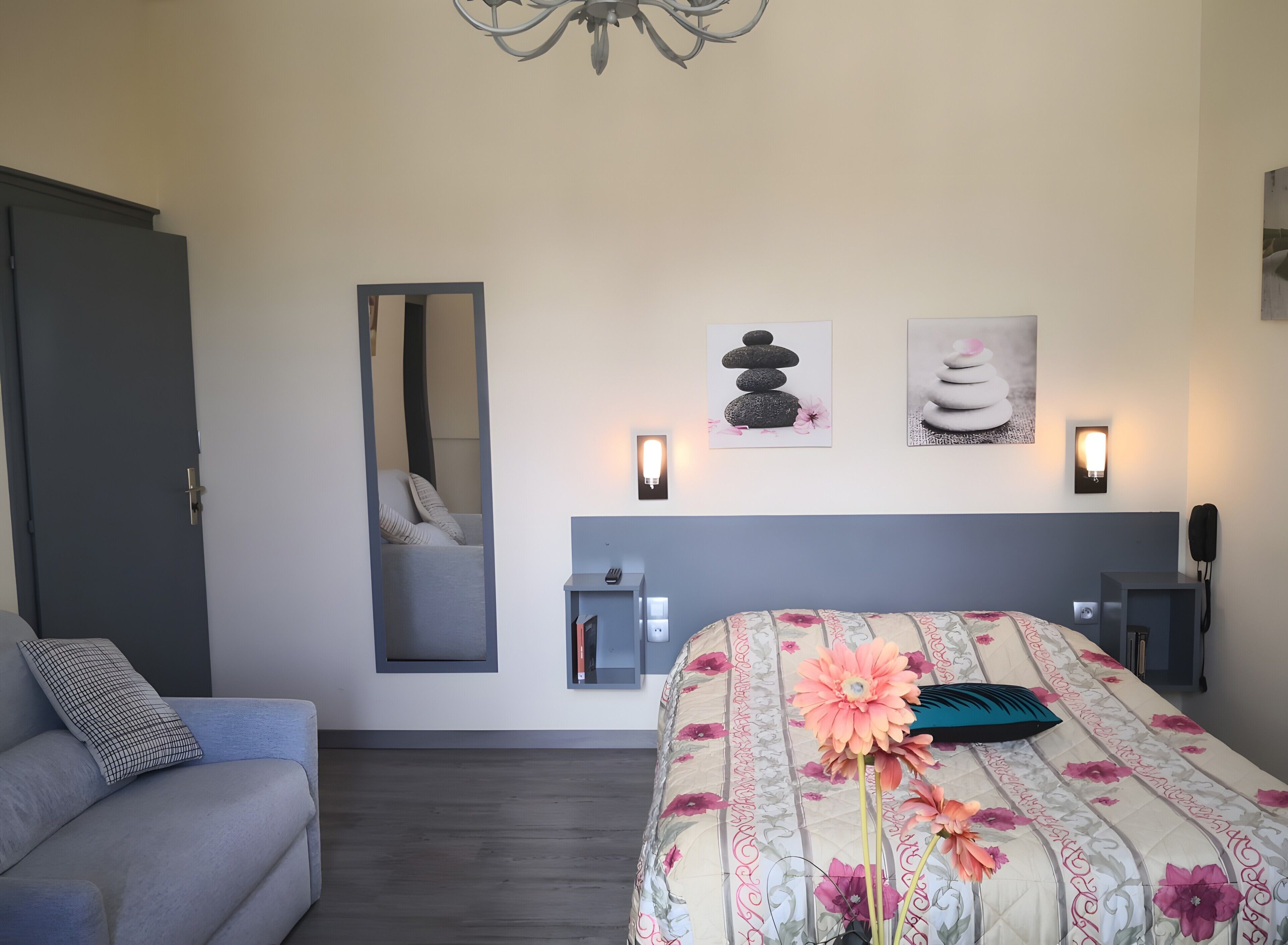 Un dormitorio con cama, sofá, espejo e iluminación en la pared.