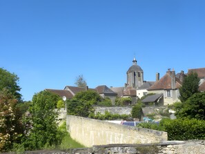 A historic building with a prominent tower, surrounded by lush greenery and a stone wall.