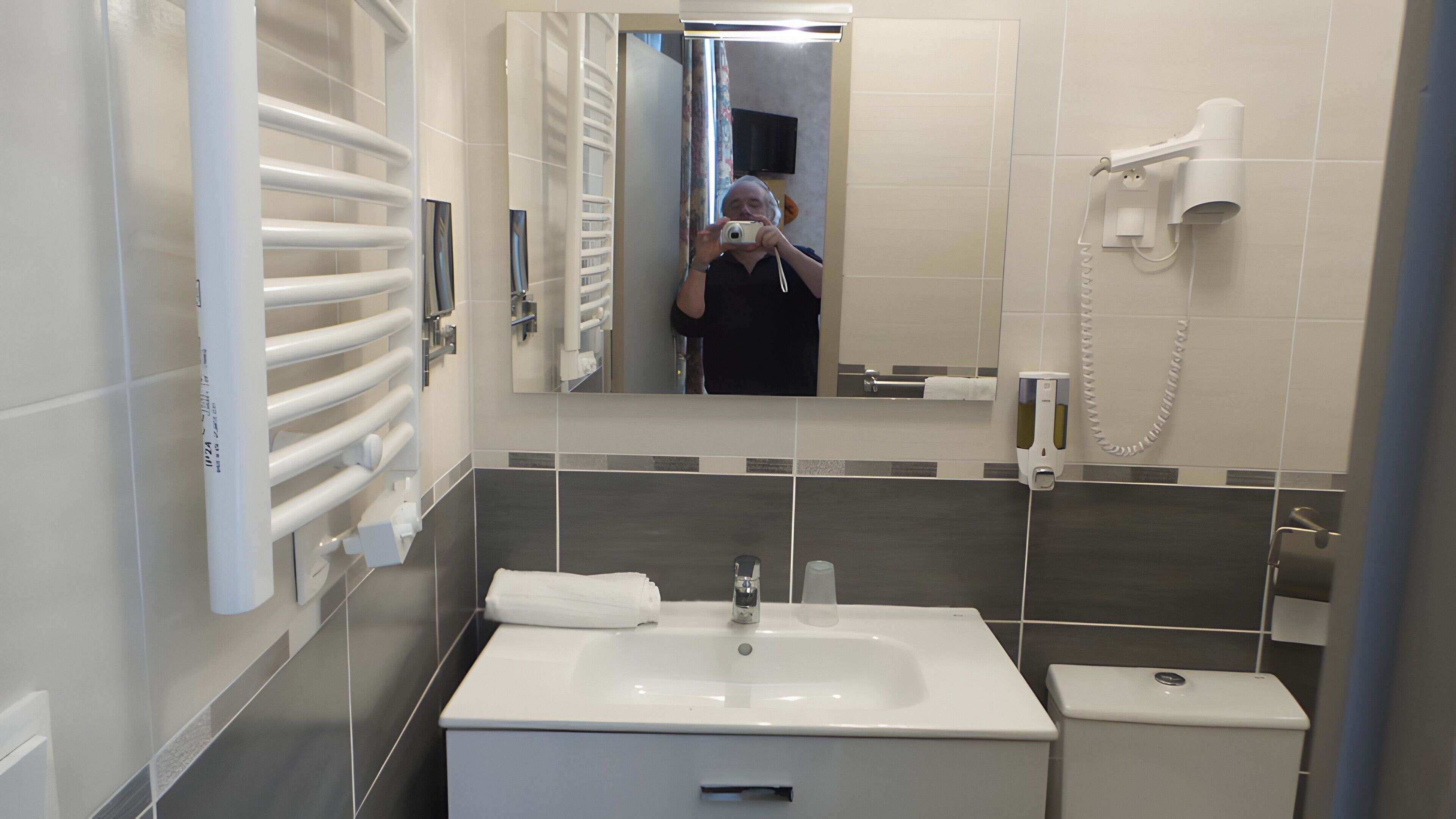 Een moderne badkamer met een wit wastafelmeubel, spiegel en handdoekrek.