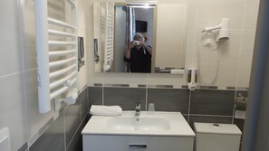 Et moderne badeværelse med en hvid vask, spejl og håndklædestang.