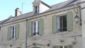 A building with multiple windows, a green door, and a small balcony with a railing.