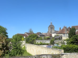 A historic building with a prominent tower, surrounded by lush greenery and a stone wall.