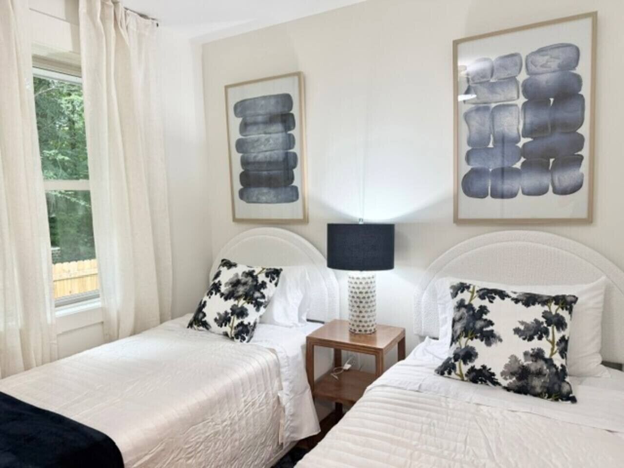A double room with two beds, a nightstand, and a lamp.