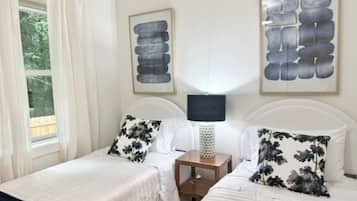 A double room with two beds, a nightstand, and a lamp.