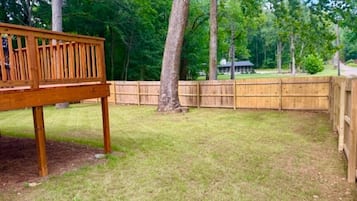 A wooden deck with a metal railing, surrounded by a wooden fence and trees.