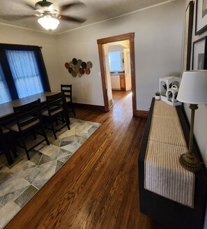 A dining area with a wooden table and chairs, a patterned rug, and a ceiling fan.