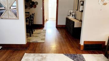 A spacious living area with a wooden floor, a central seating area, and a view into the kitchen.