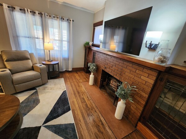 A living room with a fireplace, a television, a sofa, and a patterned rug.