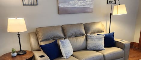 A living room with a sofa, two side tables, a coffee table, a rug, and wall art.