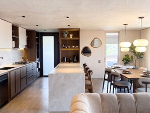 A modern kitchen with a central island, built-in cabinets, and a dining area with a wooden table and chairs. - lEPl Big & Elegant 3 Bd Apt W/Ac Near provenza (Medellín)