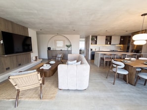 A modern living room with a sofa, dining table, and chairs, a kitchen area with a dining table, and a flat-screen TV mounted on the wall. - lEPl Big & Elegant 3 Bd Apt W/Ac Near provenza (Medellín)