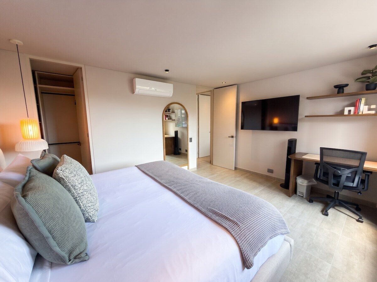 A hotel room with a bed, a desk, a chair, a TV, and a wardrobe.