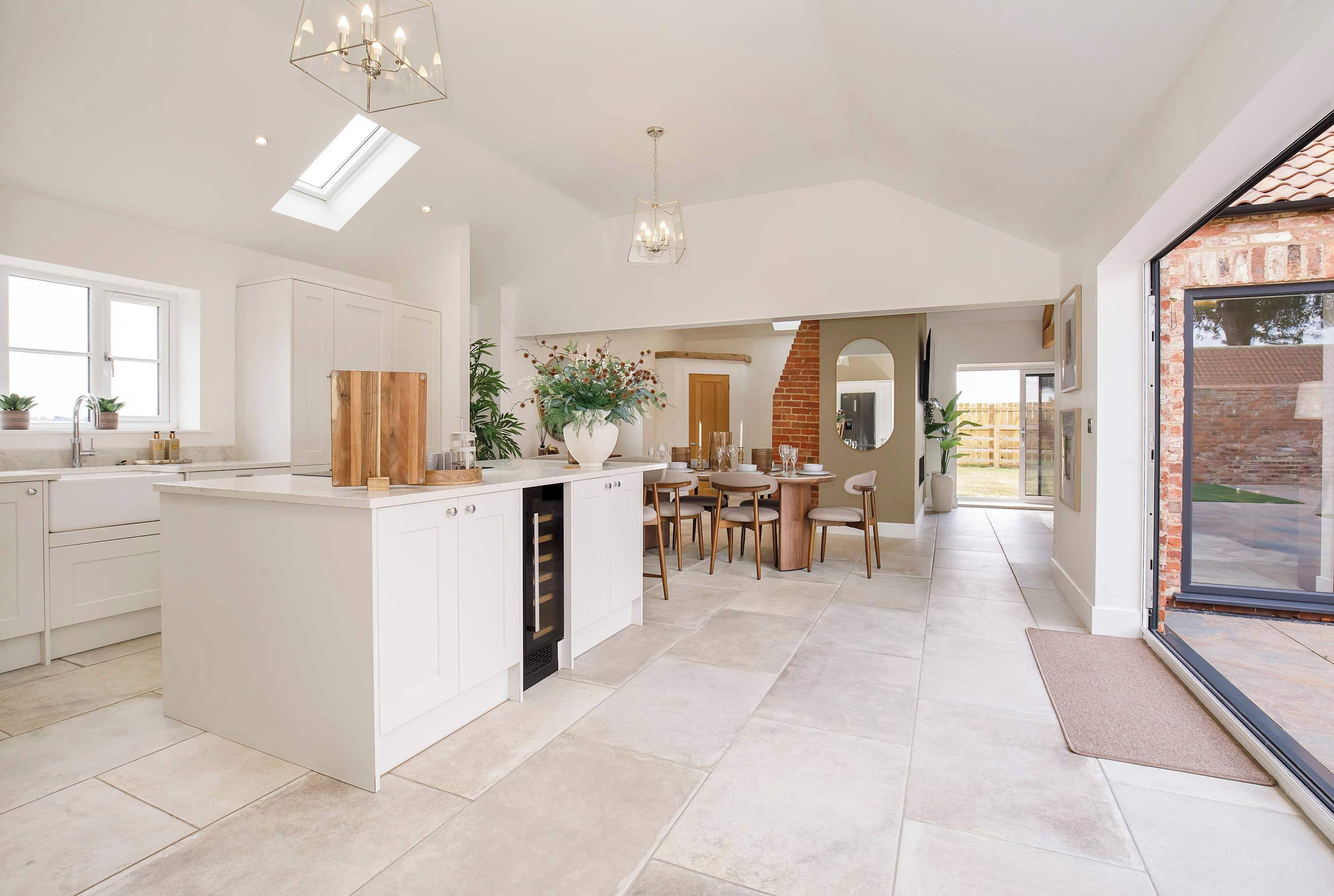 A spacious kitchen with a central island, a dining area with a brick wall, and a large sliding glass door leading to an outdoor area.