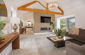 Un amplio espacio de sala con techo alto, chimenea, televisor y comedor con mesa y sillas de madera.
