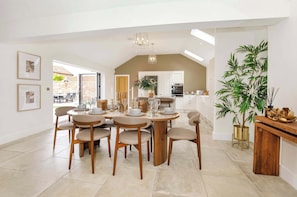 A spacious dining area with a high ceiling and a view of the kitchen. - The Smithy - Luxury Barn Conversion Cottage Malton & York, Sleeps 6 (Ryton)