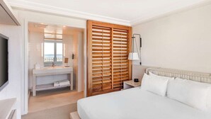 Habitación de hotel con una cama, una tocador con espejo y un separador de madera con listones.