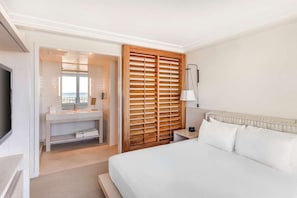 Ein Hotelzimmer mit einem Bett, einem Schminktisch mit Spiegel und einer Holztrennwand.