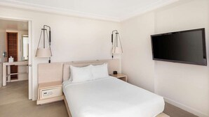 Ett hotellrum med en säng, sängbord, en tv och en spegel.
