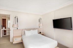Een hotelkamer met een bed, nachtkastjes, een televisie en een spiegel.
