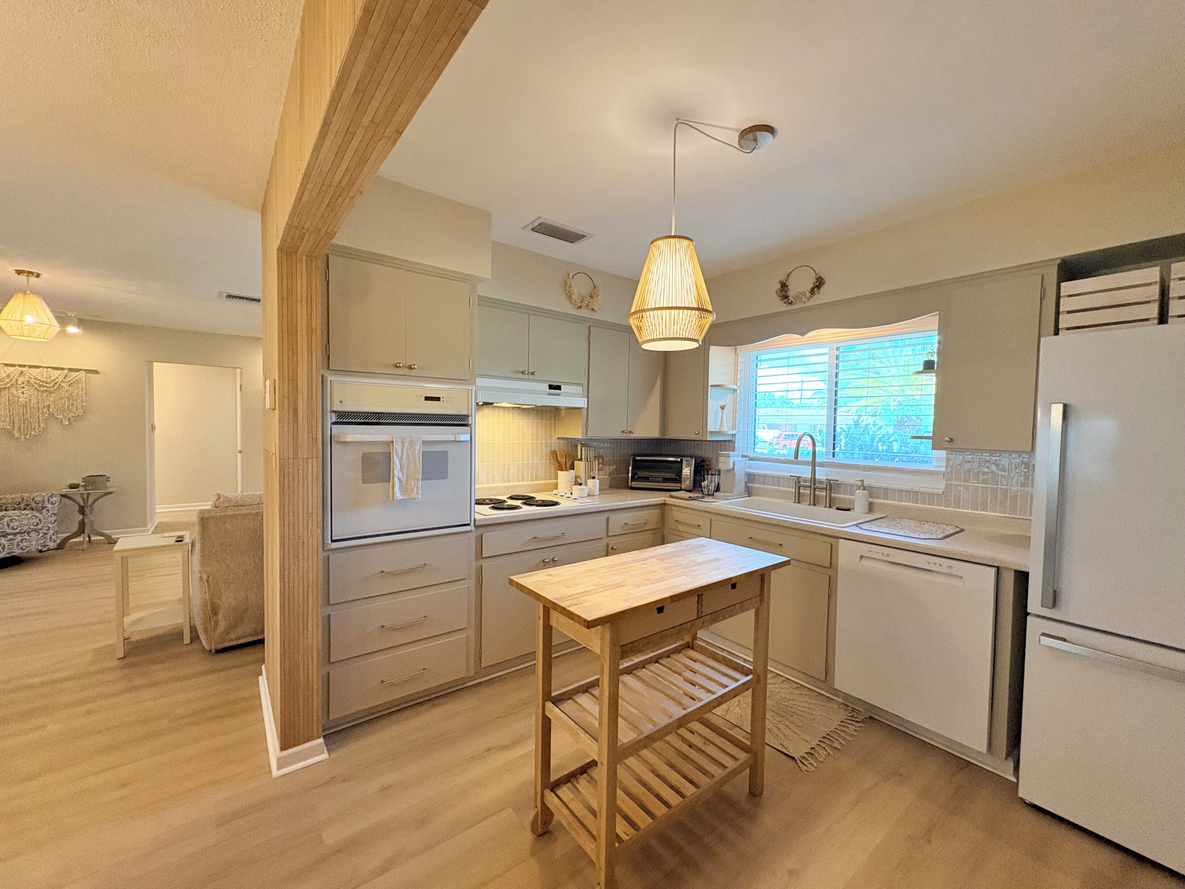 A modern kitchen with built-in appliances, a wooden table, and pendant lighting.