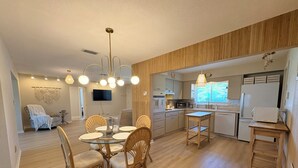 Eine moderne Küche mit Essbereich, Holzboden und einem an der Wand montierten Flachbildfernseher.