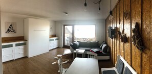 Ein zeitgemäßer Wohnraum mit Küche, Essbereich und einem Balkon mit Aussicht.