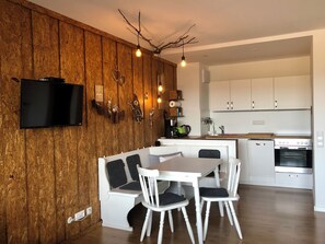 Eine moderne Küche mit weißen Schränken, einem eingebauten Backofen und einem Essbereich mit weißem Tisch und Stühlen.