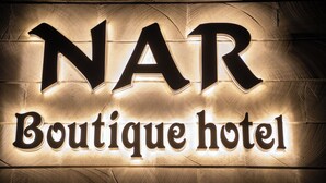 A sign with the letters 'NAR' and the words 'Boutique hotel' illuminated against a textured wall.