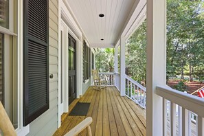 A covered porch with a wooden floor, white railings, and a view of a wooded area. - Fore Seasons Wonderful 5BR home in DeBordieu w/ super location, great porches (Georgetown)