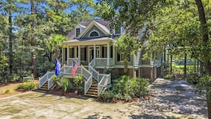 A two-story house with a porch, a flag, and a well-maintained garden. - Fore Seasons Wonderful 5BR home in DeBordieu w/ super location, great porches (Georgetown)
