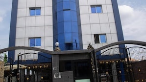 A multi-story building with a modern architectural design, featuring a central glass facade and a symmetrical window arrangement. - Champion Hotel (DOUALA)