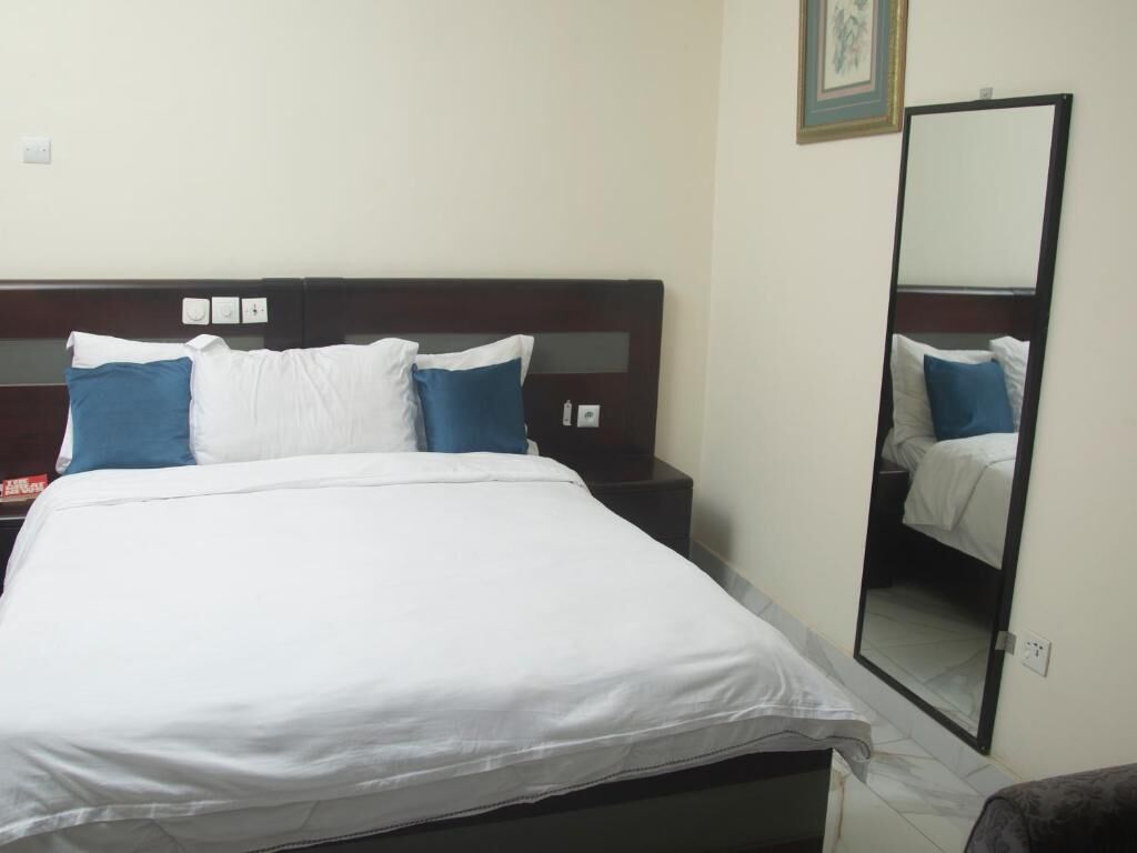 Quarto de hotel com cama, mesa de cabeceira e espelho.