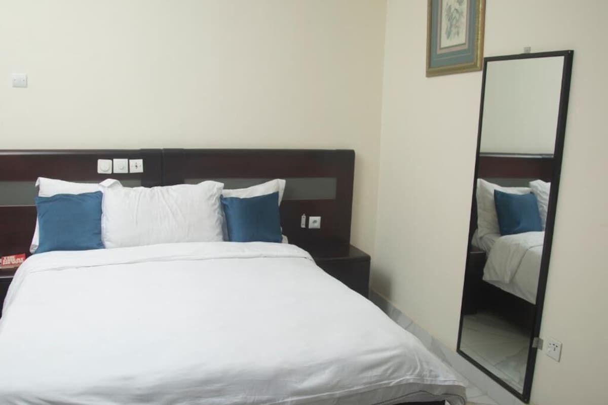 Une chambre d’hôtel avec un lit, une table de chevet et un miroir.