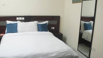Quarto de hotel com cama, mesa de cabeceira e espelho.