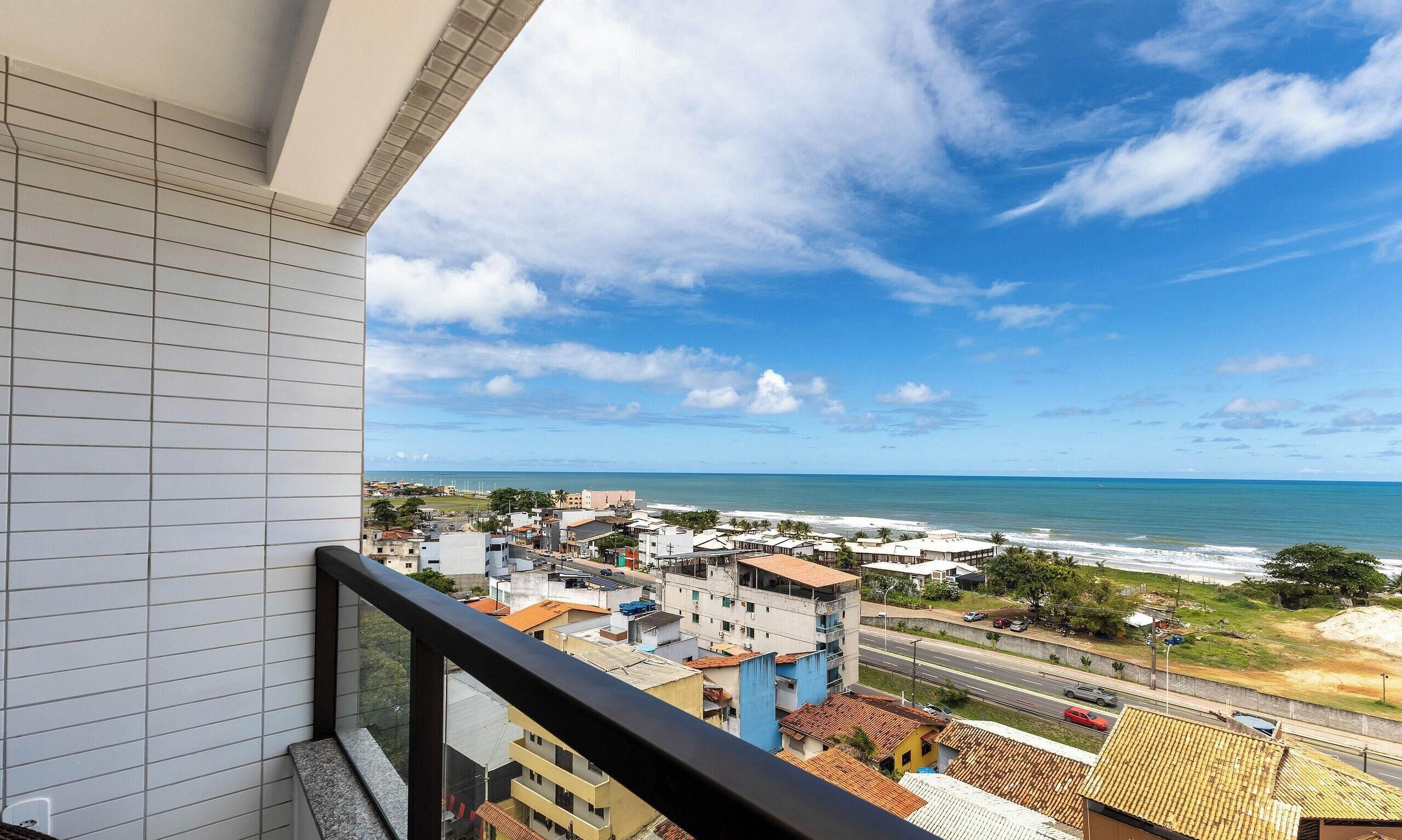 A balcony with a view of a coastal town, buildings, and the ocean.
