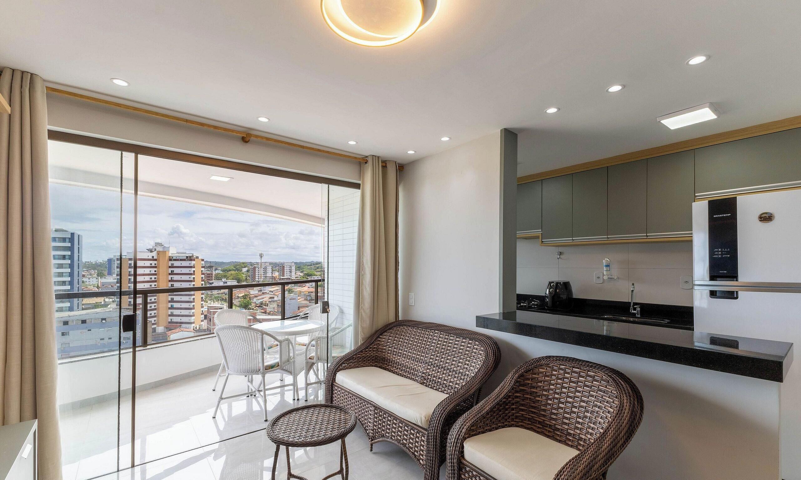 Apartamento moderno com varanda, área de jantar e cozinha compacta.