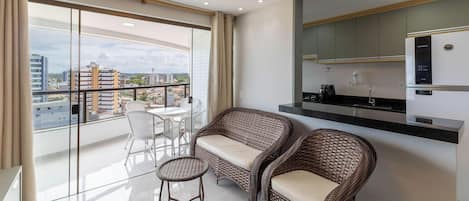 A modern apartment with a balcony, a dining area, and a kitchenette.