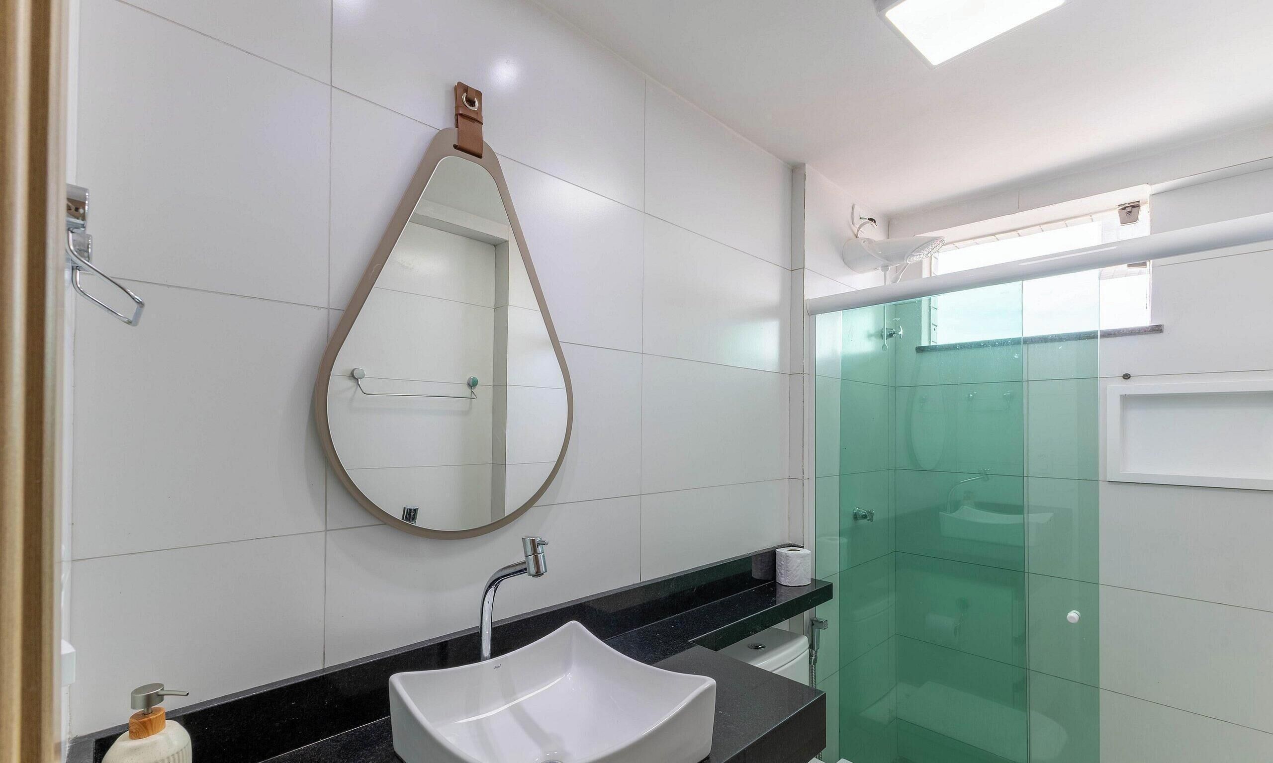 A modern bathroom with a white sink, a large mirror, and a glass shower enclosure.