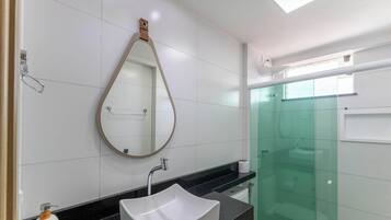 A modern bathroom with a white sink, a large mirror, and a glass shower enclosure.