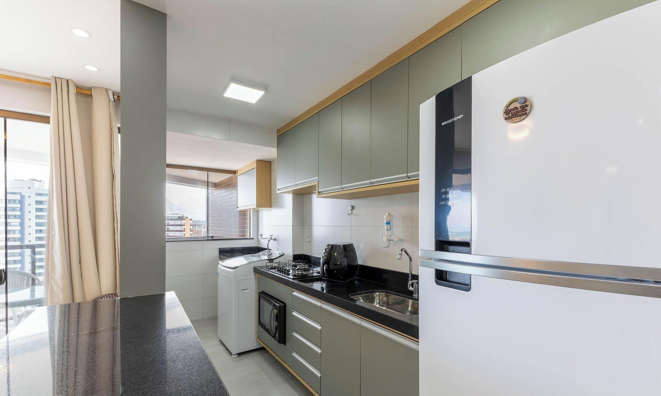 A modern kitchen with a built-in oven, a coffee machine, and a refrigerator.
