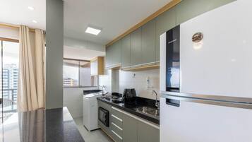 A modern kitchen with a built-in oven, a coffee machine, and a refrigerator.
