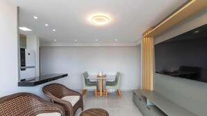 A modern living room with a flat-screen TV, wicker furniture, a dining table, and recessed ceiling lighting. - Apt Sea View 300 m From the Beach Mmd0802 (Ilhéus)