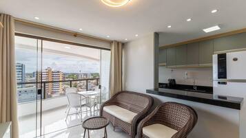 A modern apartment with a balcony, a dining area, and a kitchenette.