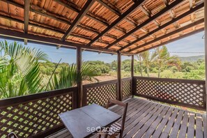 A covered outdoor area with a table and chairs, surrounded by wooden railings and a view of greenery. - 1BR Duplex w/ BBQ 350m From the Beach Vle008 (Bombinhas)