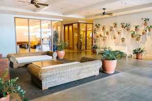 A hotel lobby with a seating area, a glass door entrance, and a wall decorated with potted plants. - Waikiki | Harborfront Getaway | Pool & Marina | Studio (Honolulu)
