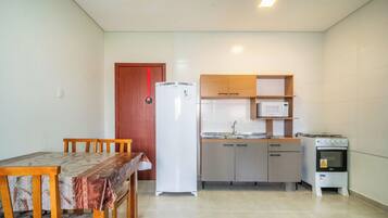 A compact kitchen with a refrigerator, microwave, stove, and wooden cabinets.