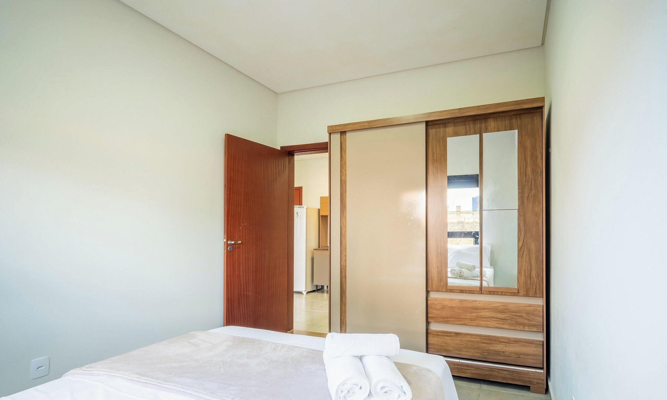 Una camera d'albergo con un letto, un armadio in legno e uno specchio.