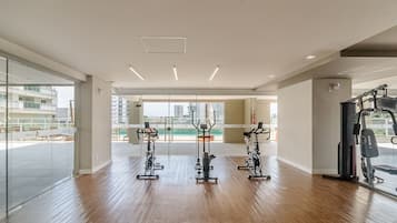 A gym with exercise equipment, large windows, and a view of buildings.