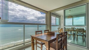 Un comedor con vistas al mar, ventanas amplias y una mesa con sillas.