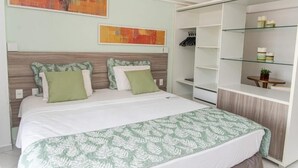 Ein Schlafzimmer mit einem Bett, einem Kleiderschrank und zwei abstrakten Bildern an der Wand.